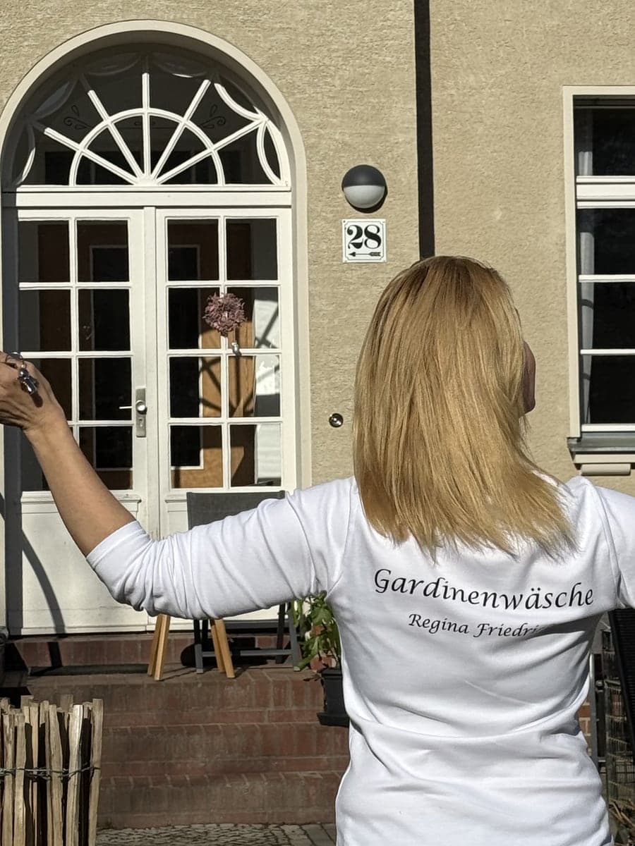Regina Friedrich im Gardinenwäsche-Shirt an einer Haustür